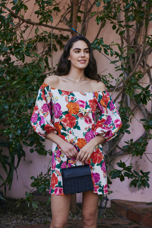 A woman wearing a white dress with an orange and pink floral design